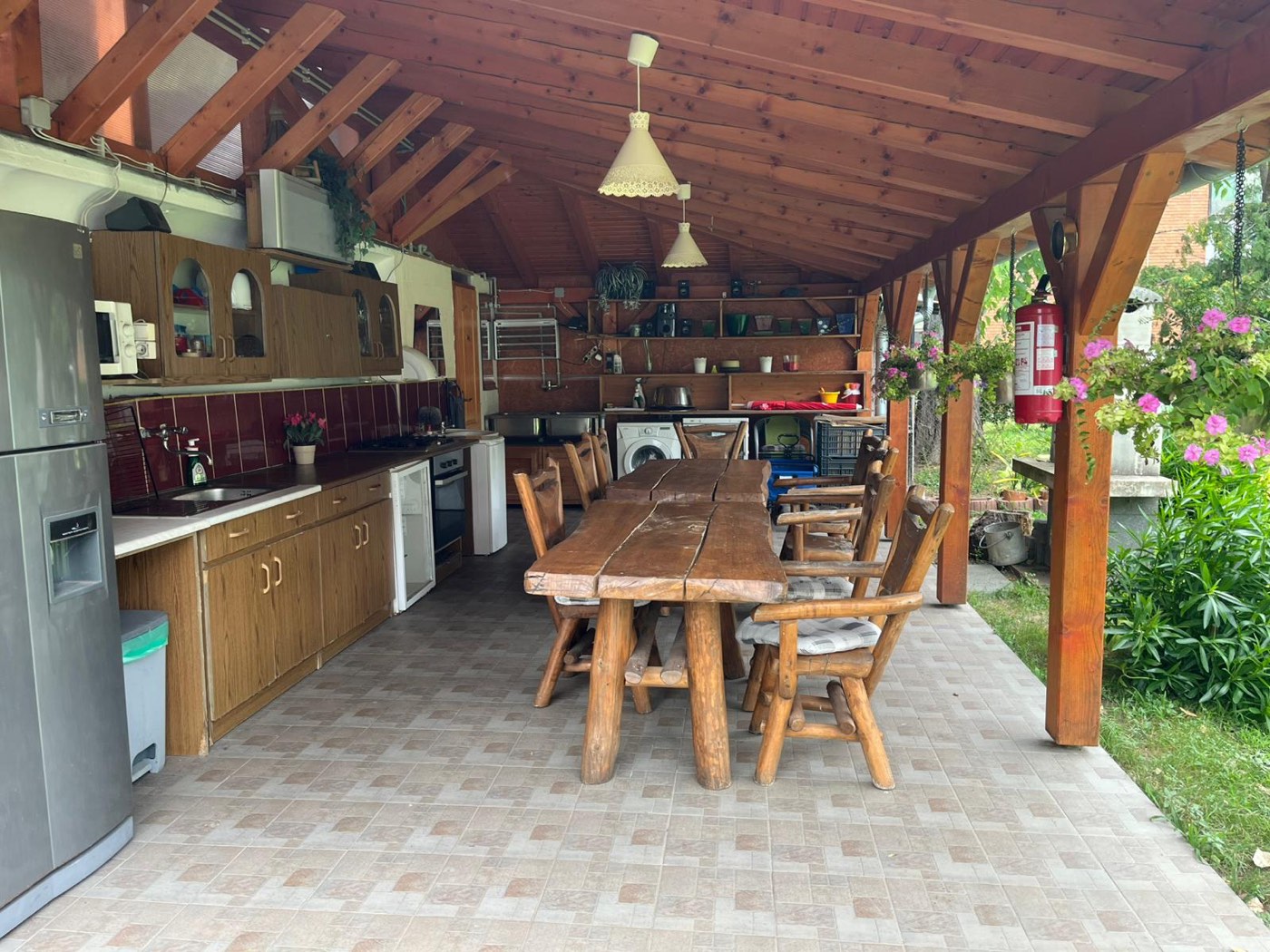 Überdachte Sommerküche mit großem gemeinsamem Esstisch